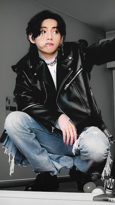 a man with black hair sitting on top of a counter