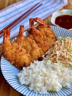 a plate with rice, shrimp and coleslaw on it next to dipping sauce