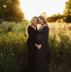 two pregnant women standing in tall grass at sunset