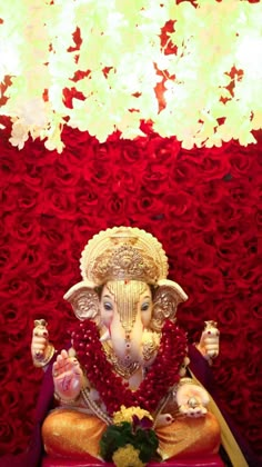 an elephant statue sitting on top of a red and gold bench next to a flower covered wall