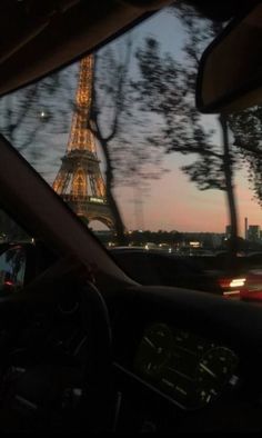 the eiffel tower is lit up at night as seen from inside a car