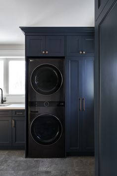 a black washer and dryer in a kitchen with blue cabinets on the wall