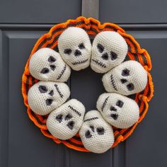 a knitted wreath decorated with skulls and orange trimmings on a black door