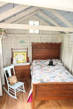 a bedroom with a bed, rocking chair and dresser in the corner next to it