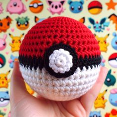 a small crocheted pokeball is held up in front of a colorful background