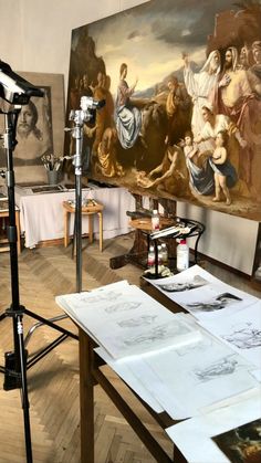 an artist's studio with paintings on the wall and a tripod in front of it