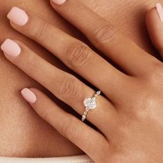 a woman's hand with a diamond ring on her left wrist and the other hand holding an engagement ring