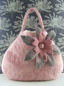 a pink purse sitting on top of a table next to a wallpapered background