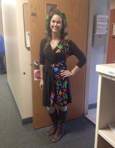 a woman standing in front of a door wearing boots and a dress with letters on it