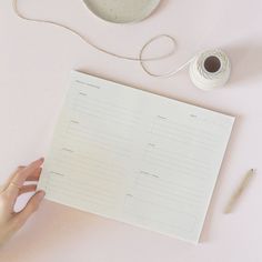 a person holding a piece of paper next to a bowl and yarn on a table