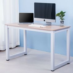 a desk with a computer and a plant on it