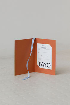 an open orange card with a white ribbon on the end and a name tag attached to it