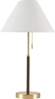 a table lamp with a white shade on the base and a gold plated base