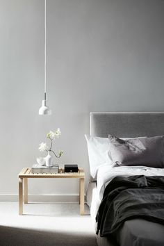 a bed room with a neatly made bed next to a night stand and flowers on a table