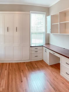 an empty room with wooden floors and white cabinets