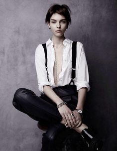 a woman in white shirt and black pants sitting on the floor with her legs crossed