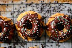 chocolate covered doughnuts with sprinkles on a cooling rack, ready to be eaten