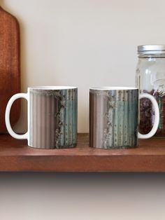 two coffee mugs sitting on top of a wooden shelf next to a mason jar