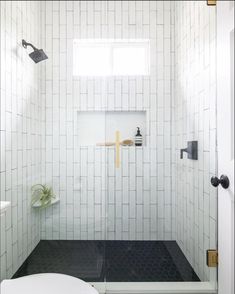 a bathroom with white tile and black flooring