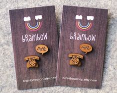 two wooden brooches with the words brainbowk and hello phone on them