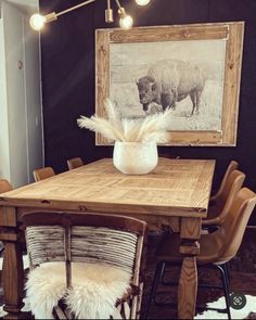 a dining room table with chairs and a cow print on the wall