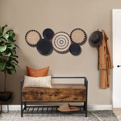 a wooden bench sitting in front of a wall with hats hanging on it's sides