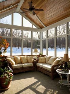 a sun room with lots of windows and furniture