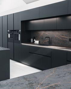 a kitchen with black cabinets and marble counter tops is seen in this image from the front view