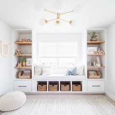 a white room with lots of shelves and baskets on the floor, along with a window seat