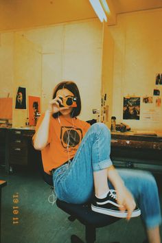 a woman sitting in an office chair while talking on the phone and listening to headphones