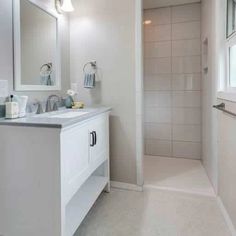 a white bathroom with two sinks and a shower