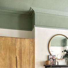 a room with a dresser, mirror and potted plant on it's shelf