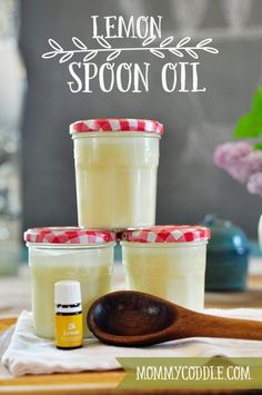 lemon spoon oil is sitting on a table next to three jars and a wooden spoon