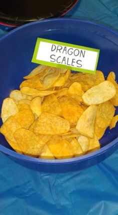 a blue bowl filled with chips and a sign that says dragon scales on it's side