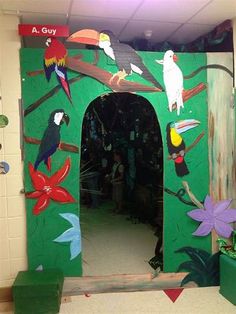 a green wall with birds painted on it and people standing in the doorway looking at them