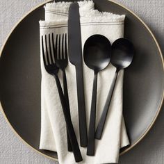 black utensils are sitting on a plate with white napkins and silverware