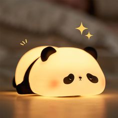 a lamp that looks like a panda bear laying down on the floor with stars above it