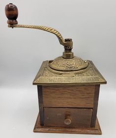 an old fashioned wooden box with a metal hook on the top and a brass plated handle