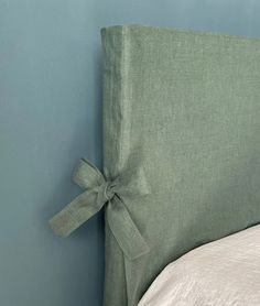 the headboard of a bed with a bow on it's back end, against a blue wall