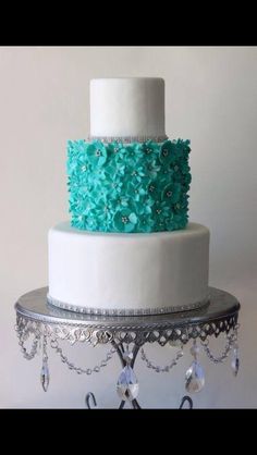 a three tiered cake with blue flowers on it's top and silver stand