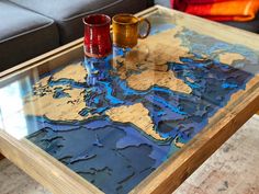 two cups are sitting on top of a glass table that is shaped like the world map