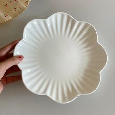 a hand holding a white plate with red sprinkles on it and another person's finger next to it