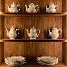 teapots, plates and cups are arranged on wooden shelves