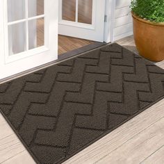 a door mat that is on the ground in front of a house with a potted plant