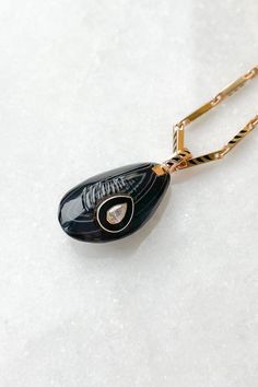 Agate Mussel with Diamond Charm from Dezso by Sara Beltran Hand-carved line agate in the shape of a mussel shell Raised center diamond set in black enamel and 18K gold 18k gold bale with black fin enamel Charm measures approximately 1" length (including bale) x 0.3" width Hand-carved in Jaipur, India