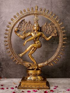 a golden statue with an intricate design on it's body and arms, surrounded by petals