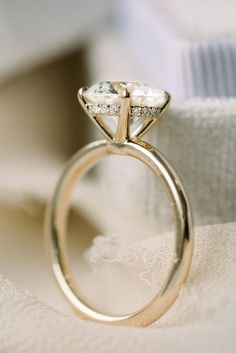 a close up of a diamond ring on top of a white cloth covered tablecloth