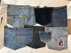 five pairs of jeans with stickers on them sitting on a white tray next to a marble counter top