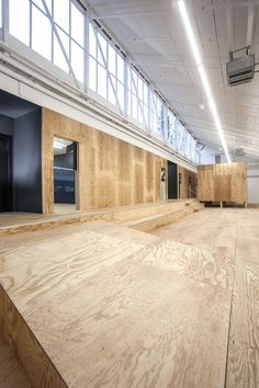 an empty building with wooden floors and windows on each side, in the middle of a large open area