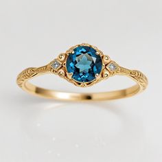 a gold ring with a blue topazte and diamond accents